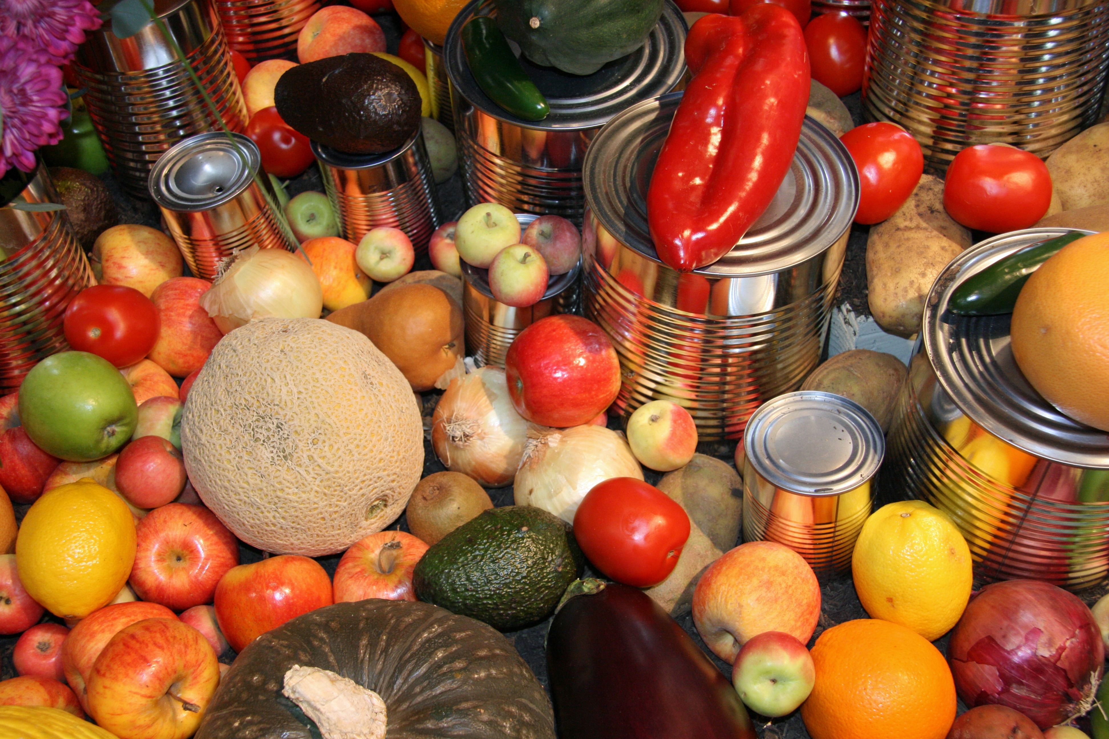 Assorted colorful fruits and vegetables with stacked canned foods on display