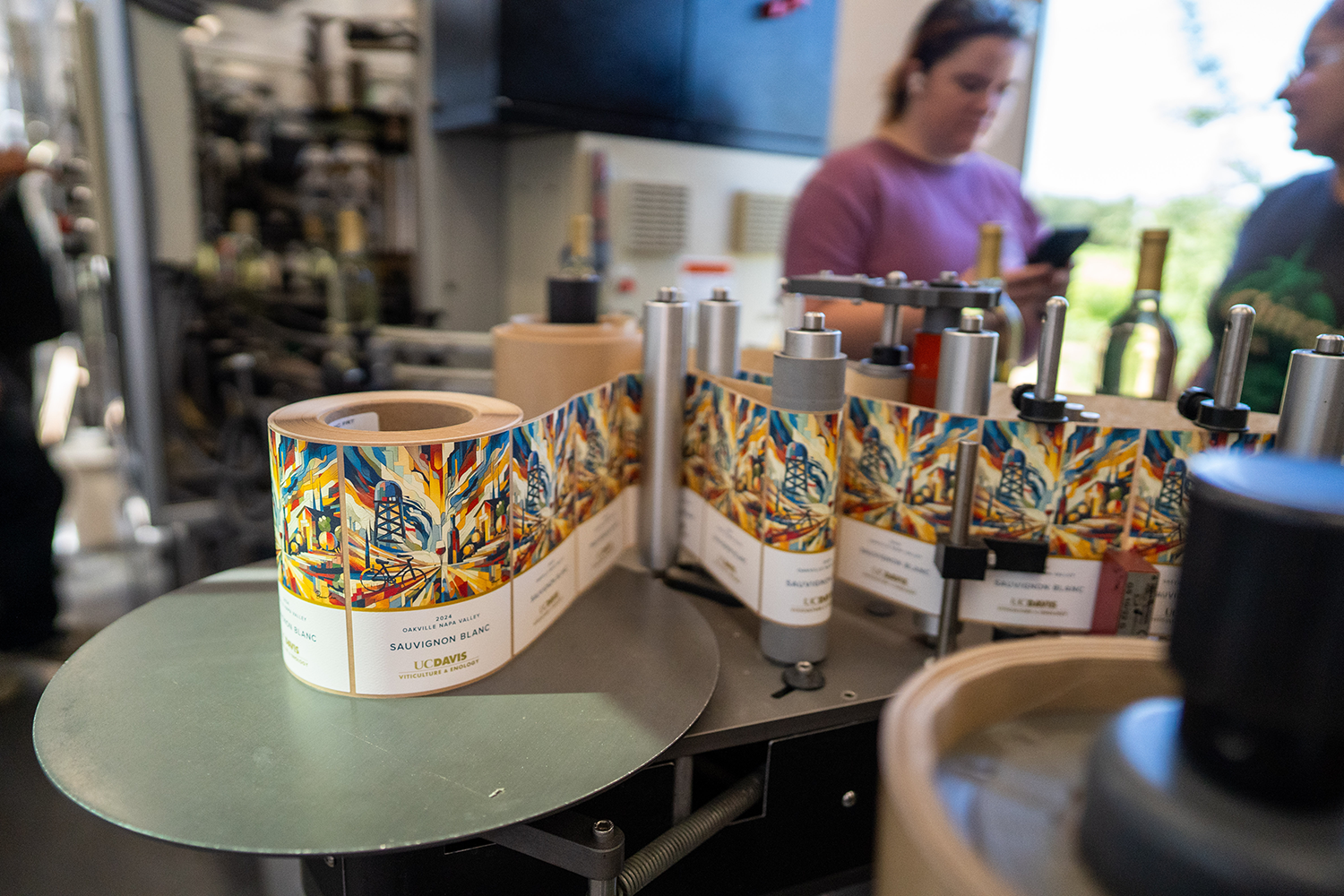 Empty bottles being filled with sauvignon blanc on a mobile bottling line, which students learn to use as part of a winemaking course. (Jael Mackendorf / UC Davis)