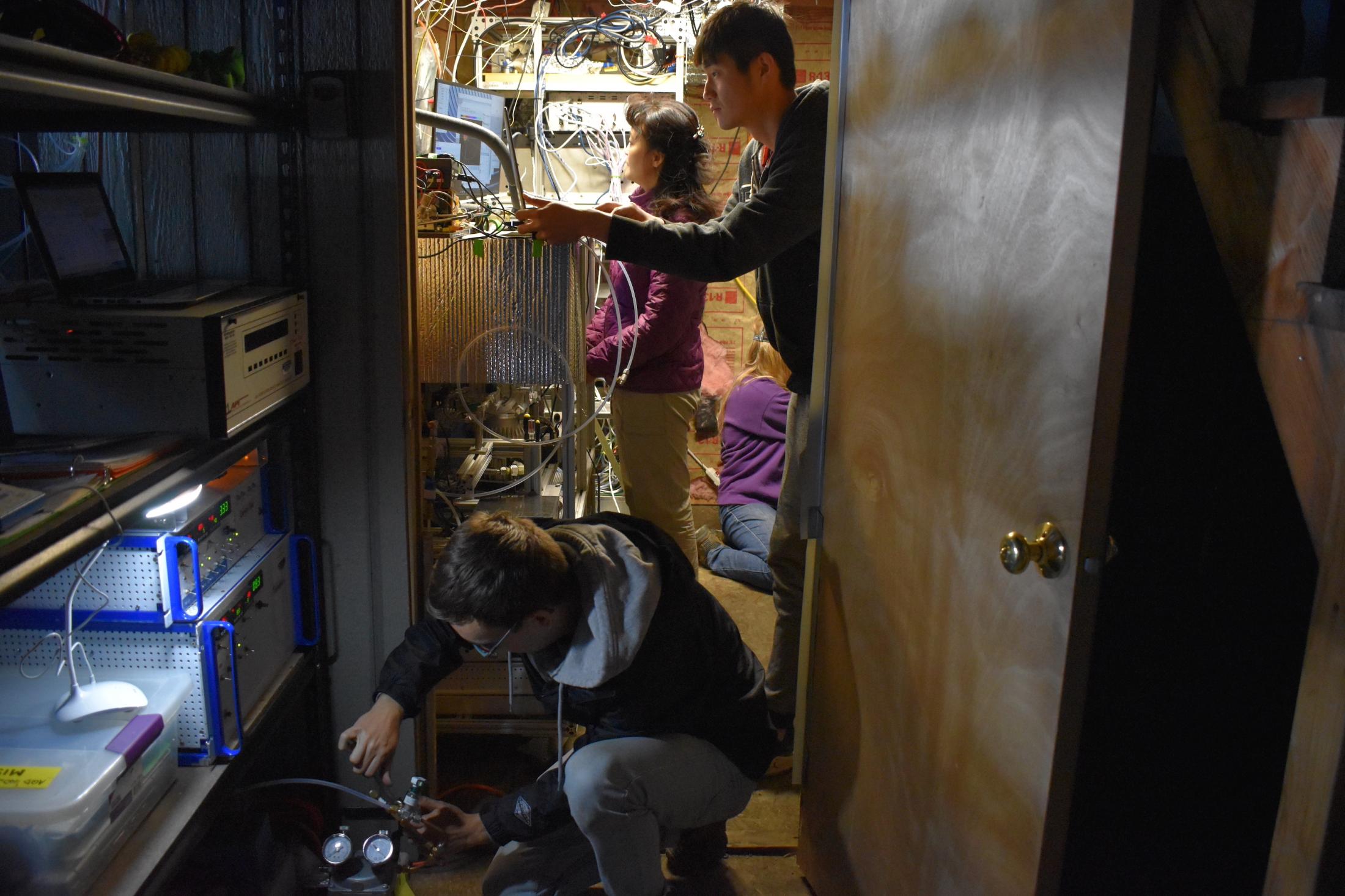 The UC Davis team sets up instruments for real-time ambient sampling at the Mount Bachelor Observatory in Oregon. Graduate student Christopher Niedek (front) sets up a particle generation system while Qi Zhang (middle) tunes a Soot Particle Aerosol Mass Spectrometer and graduate student Peng Sun works on the sampling line. (Ryan Farley/UC Davis)
