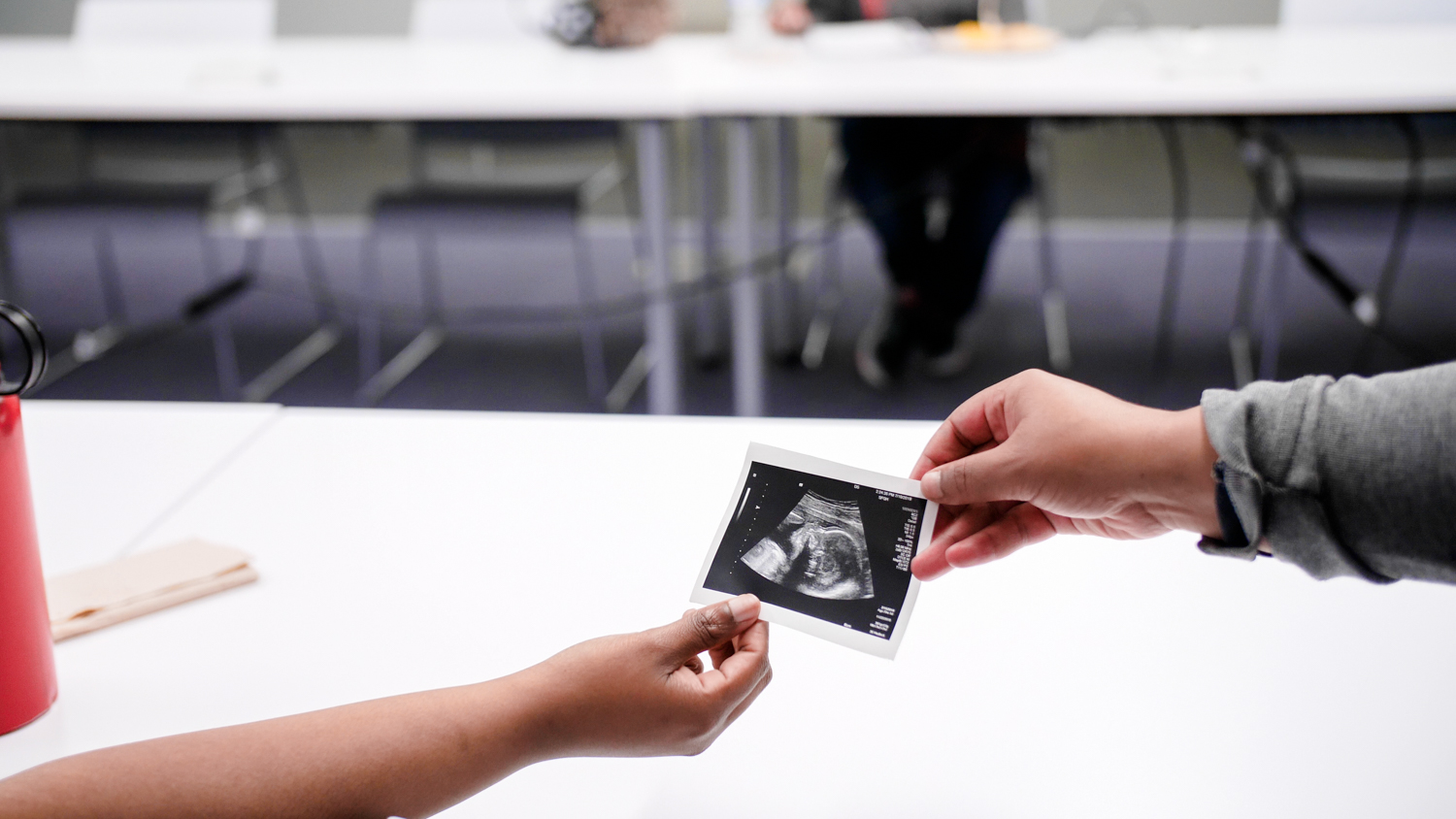 Two people use hands to hold an ultrasound image
