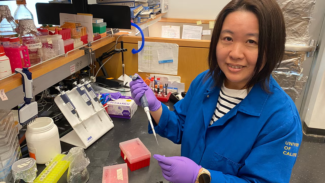 A woman in a lab coat holds a scientific instrument.