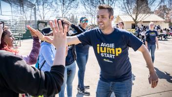 Aggie Jumpstart staff leader high fives a student.