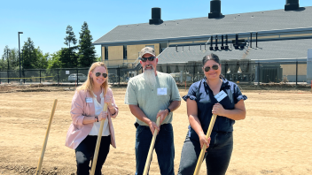 Three staff members pose with golden shovels.