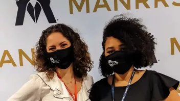 Two people stand in front of a MANRRS step and repeat banner.