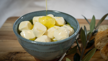Olive oil being poured over mozzarella balls.