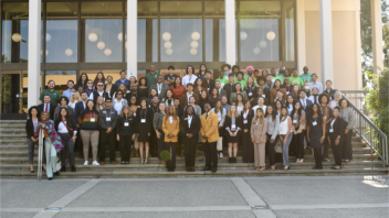 A group of people stand together in front of Olsen Hall.