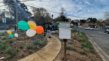 Little library pop up in the redesigned bus stop has balloons tied on it for the ribbon cutting celebration.