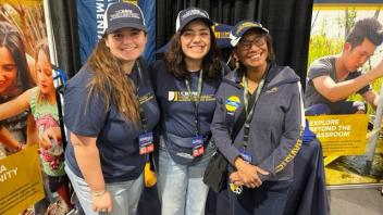 Two students pose with Dean Helene Dillard at the UC Davis booth in Tulare, CA during World Ag Expo.