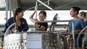 Students, in VEN 124L Winemaking Laboratory, are mixing the yeast into the fresh grapes.