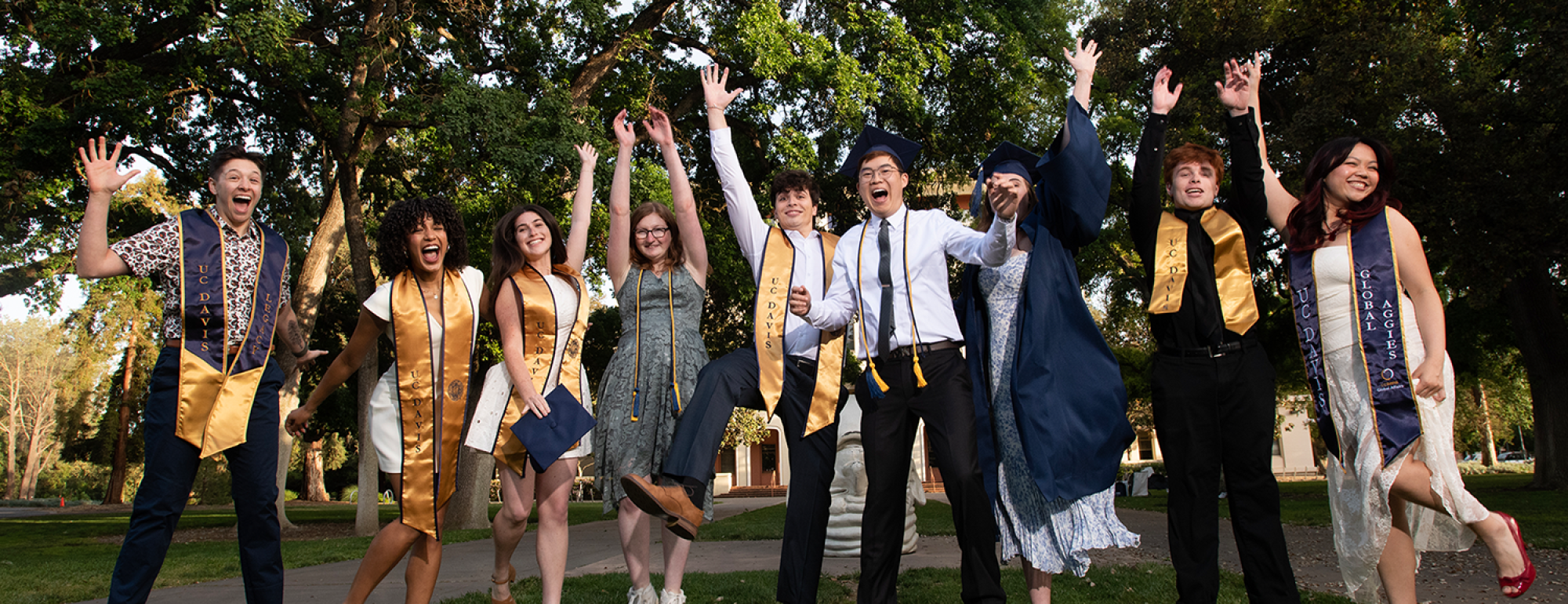 Students in caps and gowns jump in the air in celebration.