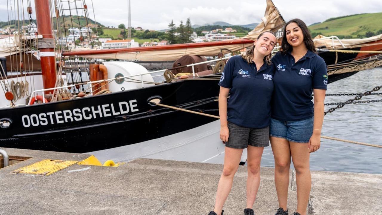Two women standing together on a dock next to a boat.