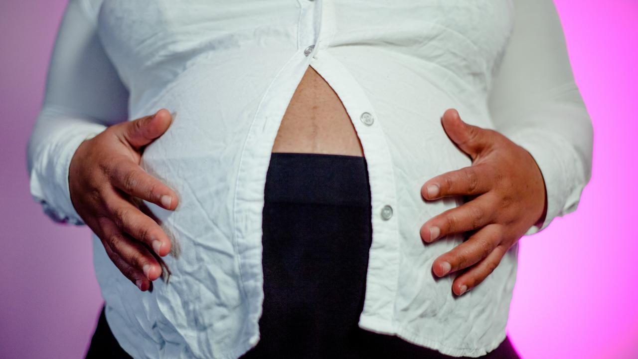 A pregnant woman holds her hands on her belly.