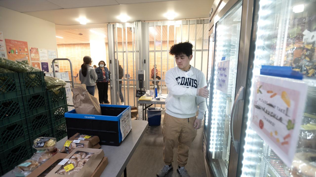 Students stocking the shelves at the Pantry on May 3, 2023. The Pantry serves to provide nutritious food for UC Davis students who are struggling to pay for meals for free. Christopher Hin, global disease biology major, works at moving cakes into the refrigerator. (Photo credit: UC Davis/Gregory Urquiaga)
