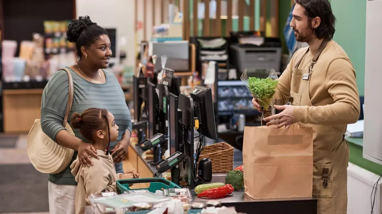Woman and daughter checking out at grocery store