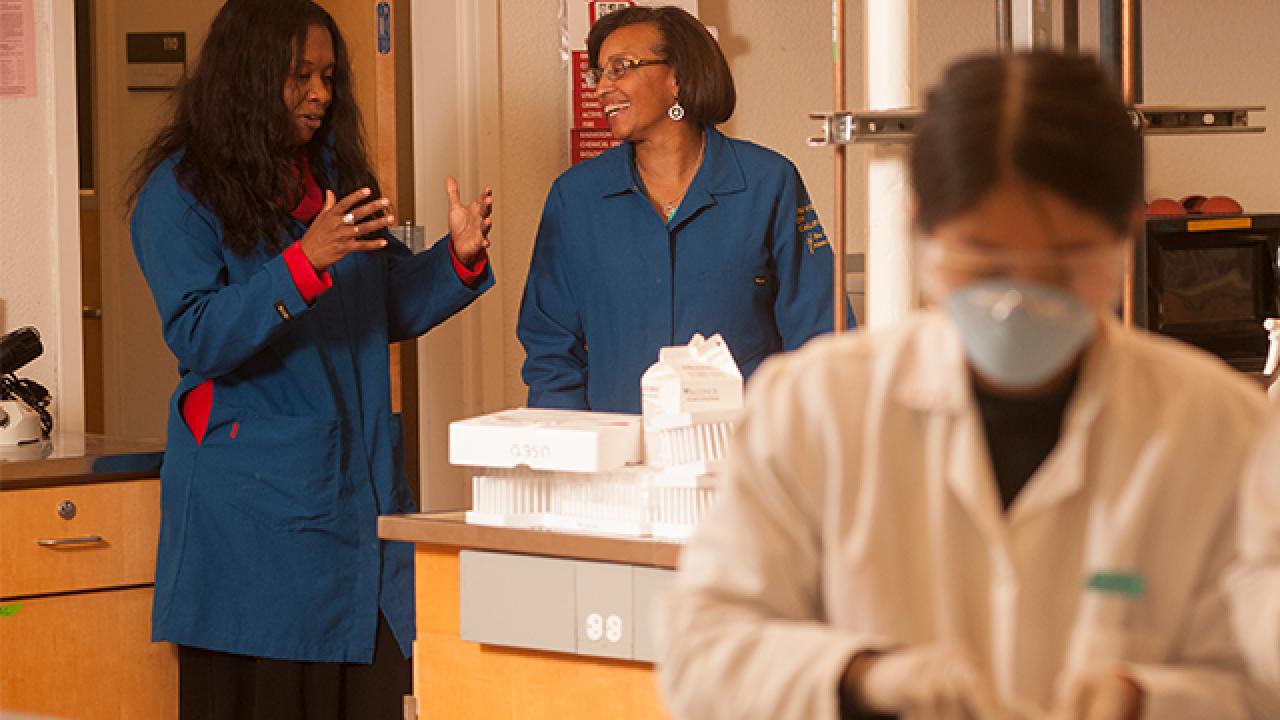 Dean Helene Dillard and professor Dianne Beckles talk as students work during a genetics and biotech lab class.