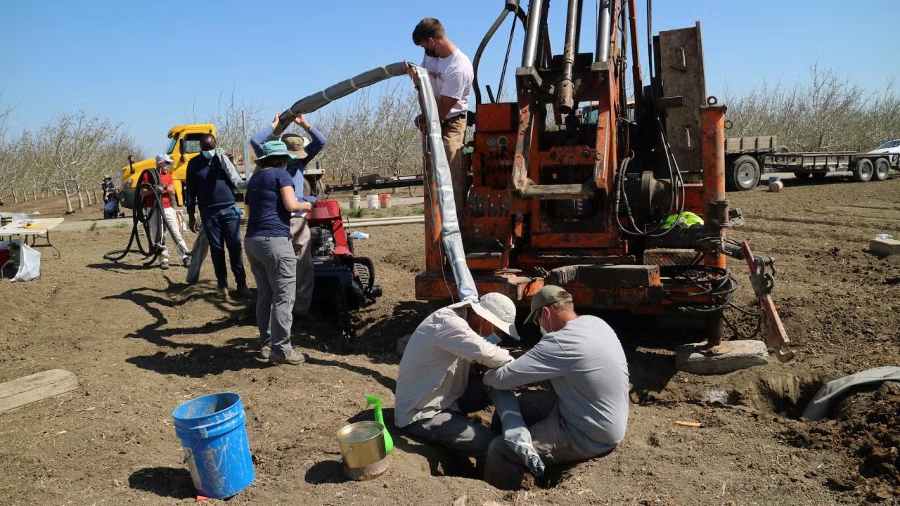 UC Davis researchers insert a device that continuously collects water samples underground, providing real-time data on nitrate contaminant movement. (Isaya Kisekka / UC Davis)