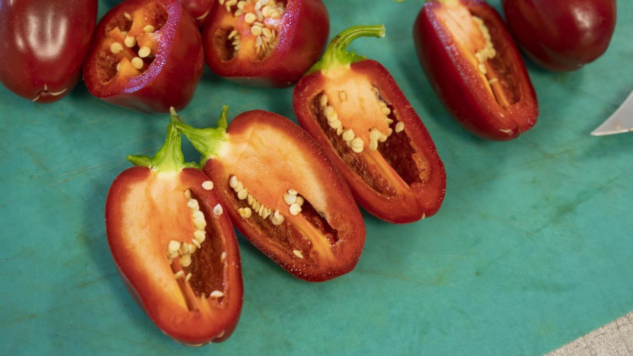 Red jalapeños sliced on a cutting board.