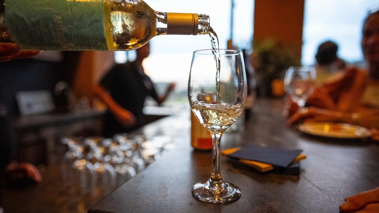 Wine pouring into a glass with a restaurant as background