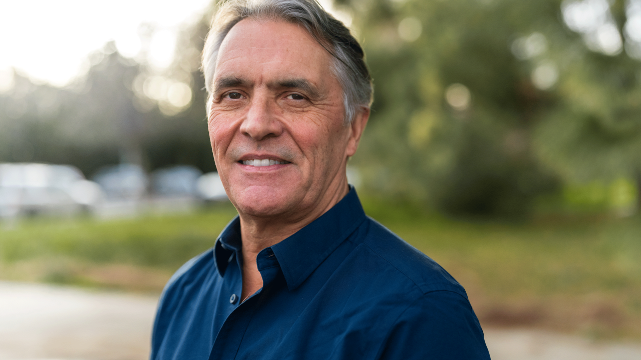 John Eadie wearing a blue button down shirt stands outside on the UC Davis campus.