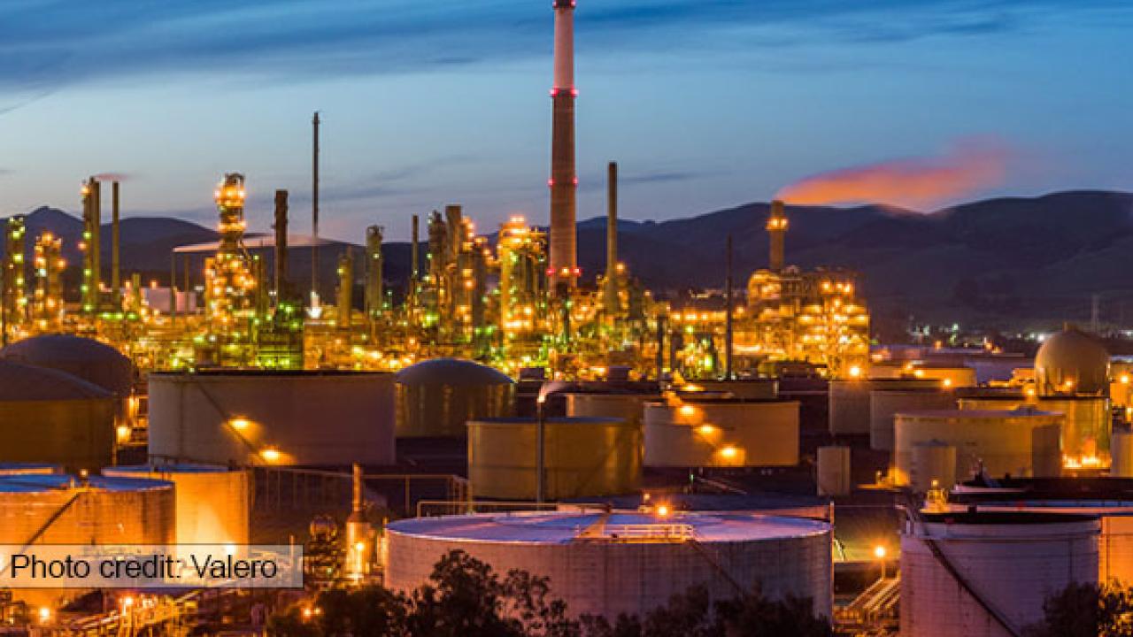 An oil refinery set against a sunset