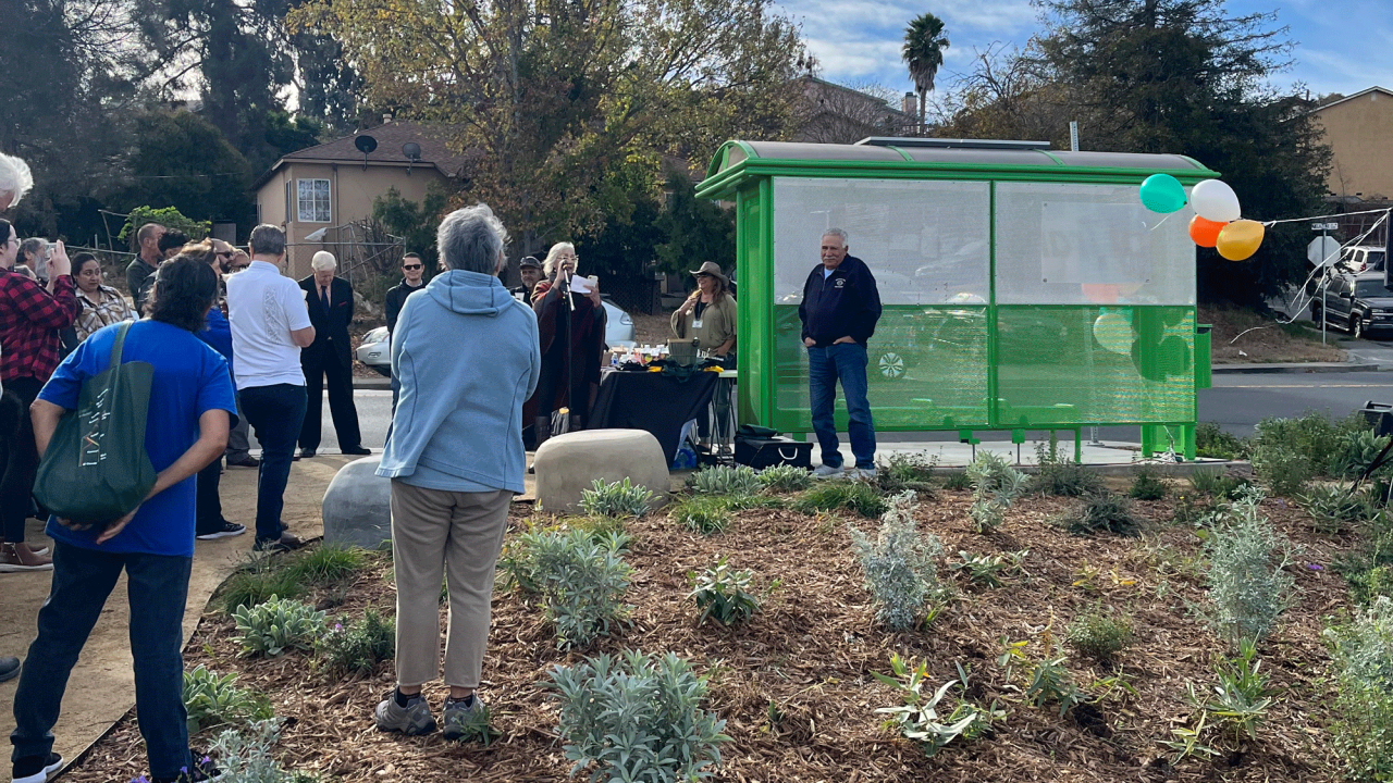 People gather at the ribbon cutting for the newly-redesigned bus stop.