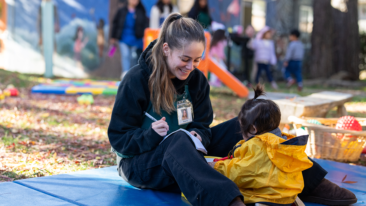 A woman playing with a child outside.