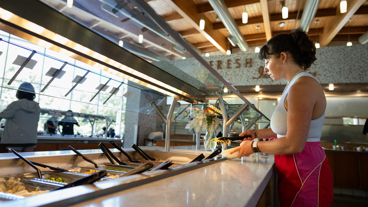 Melina Dimick, a clinical nutrition major, is preparing a plate of food at the Segundo Dining Commons. It’s part of a research project to help develop a new app that aims to encourage healthy eating habits. Photo by: Jael Mackendorf, UC Davis