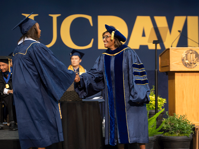 A student shakes hands with Dean Helene Dillard.