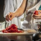 Hands preparing tomatoes to make canned tomato sauce.