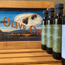Bottles of 2022 Olio Nuovo olive oil lined up on the right in front of a wooden box that says UC Davis Olive Oil.