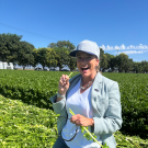A person eats a stalk of celery while standing in a field.
