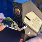 A handheld machine examines a green leaf.