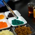 Tweezers lift a boba pellet from a tray of green boba.