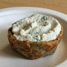 Savory bite-sized quiche topped with ricotta cheese on a paper plate.