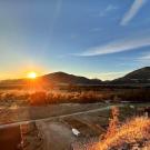 Sunset over mountains with a clear sky and orange hues illuminating the landscape.