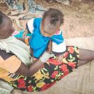 A mother holds a child on her lap.