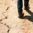Feet walking across parched ground in California.