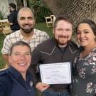 Four people gather together to take a photo with an award.