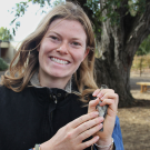 A person holds a bird gently in her hand.