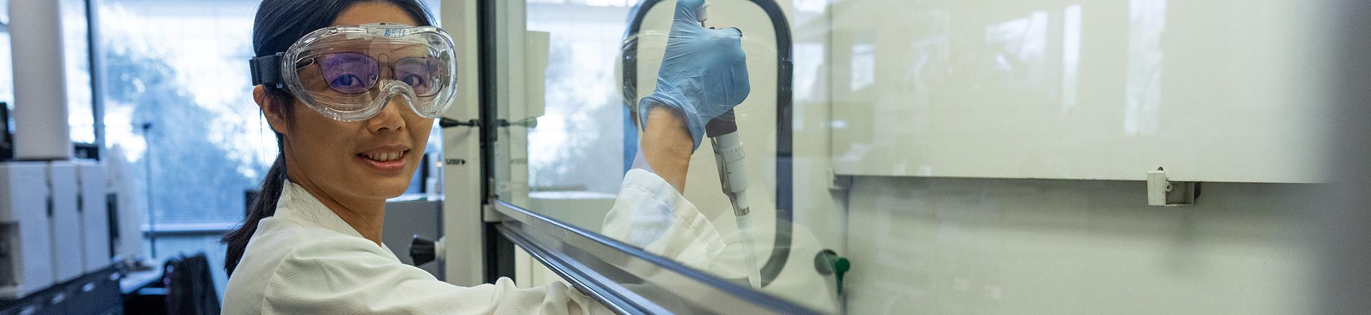 Woman work in a lab and wearing a lab coat.