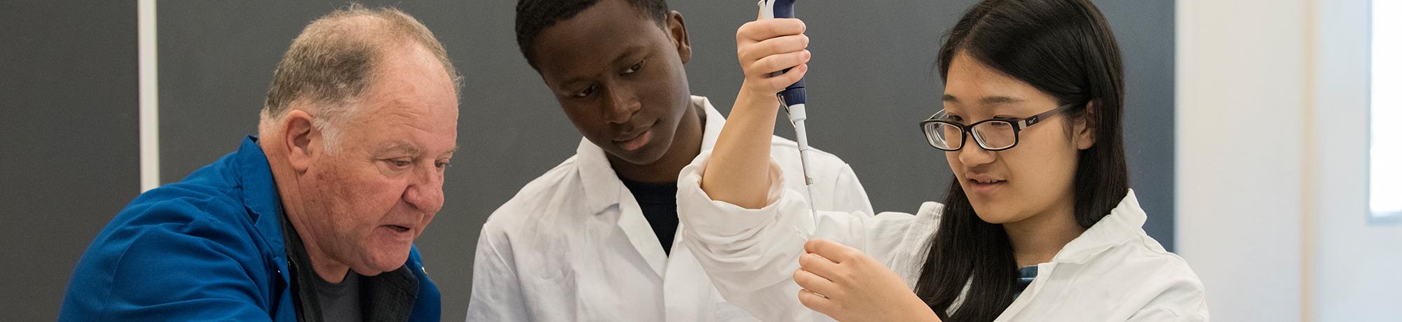 Students working with a faculty member in a lab.