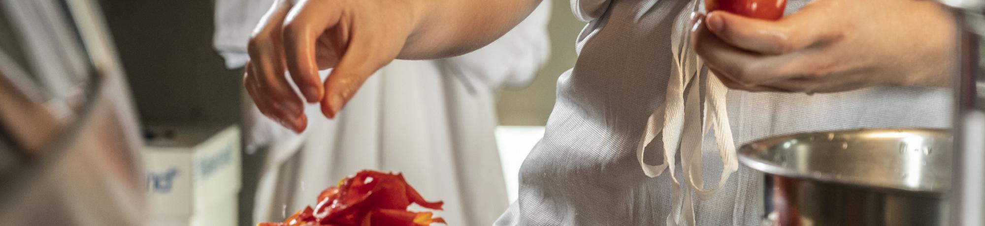 Hands preparing tomatoes to make canned tomato sauce.
