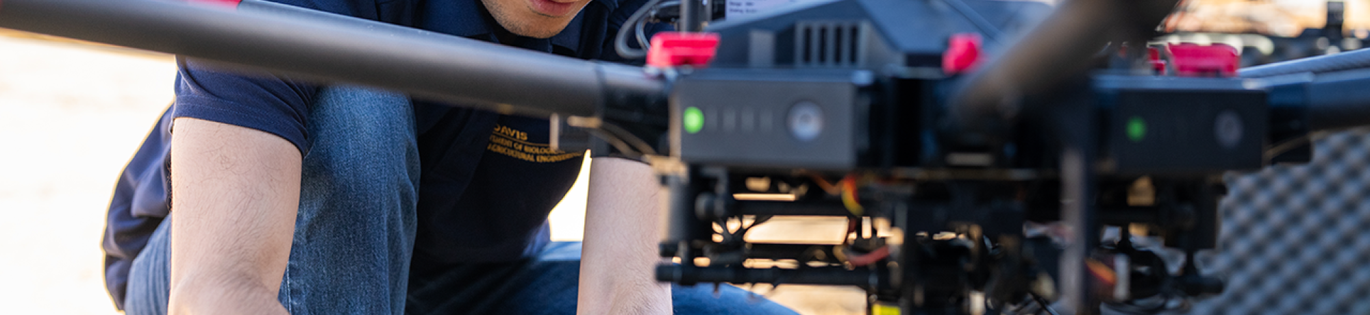 A person is handling the drone, possibly preparing it for flight in an outdoor setting