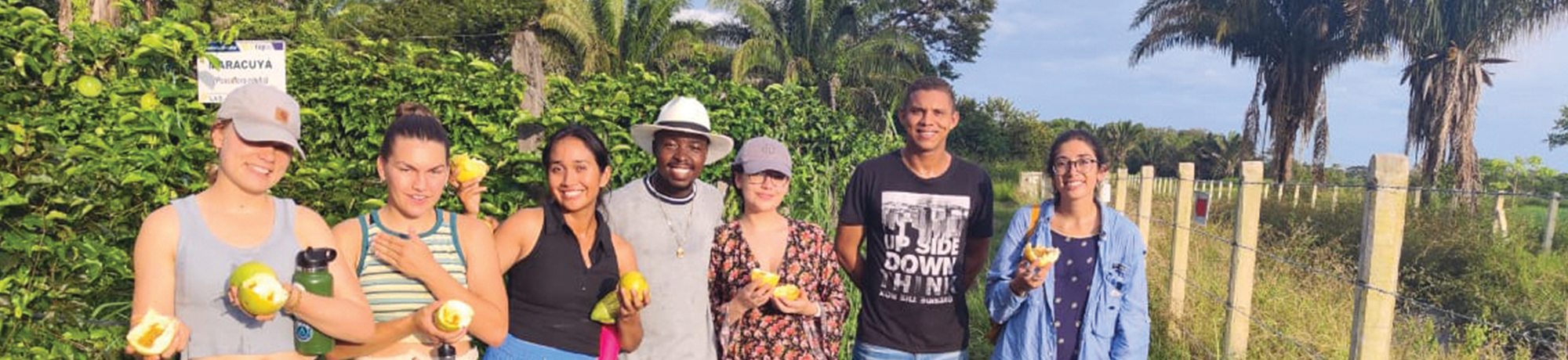 People standing together outside holding up fruit.