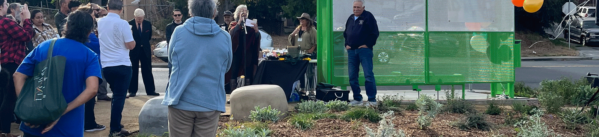 People gather at the ribbon cutting for the newly-redesigned bus stop.