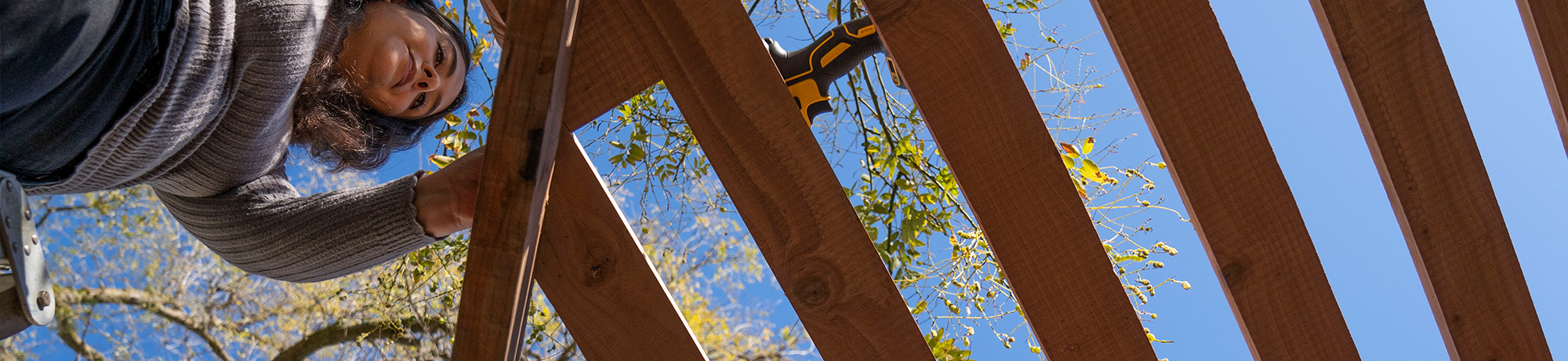 A student building the roof of a pergola.